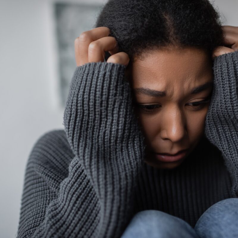 woman with anxiety in recovery curled up in a ball upset