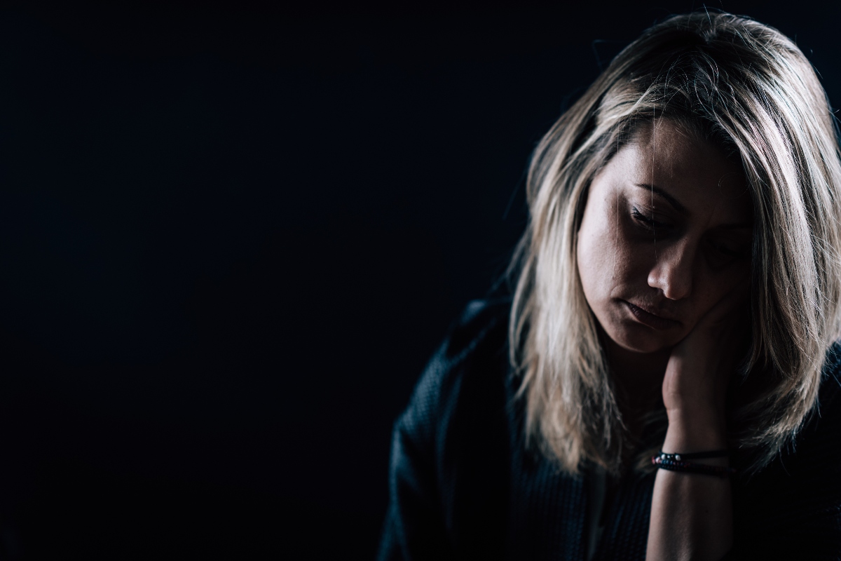 depressed woman in dark room seasonal depression and addiction